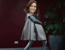 a woman in a dress is dancing in front of a plant