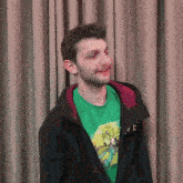 a man wearing a green shirt with a cartoon character on it is smiling