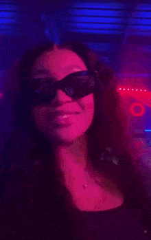 a woman wearing sunglasses is standing in front of a purple light