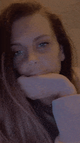 a close up of a woman 's face with her hand on her face