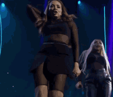 two women are dancing on a stage with a microphone .