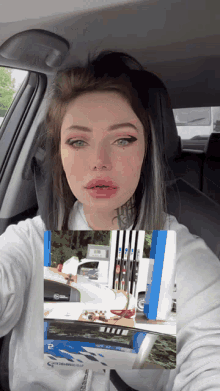 a woman is sitting in a car holding a picture of a gas pump