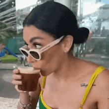 a woman wearing sunglasses is drinking a drink from a cup .