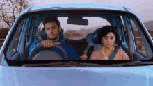 a man and a woman are in a blue car