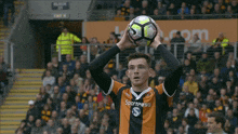 a man in a sportpesa jersey holds a soccer ball in his hand