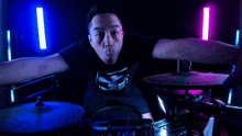 a man is making a heart shape with his hands in front of a drum set