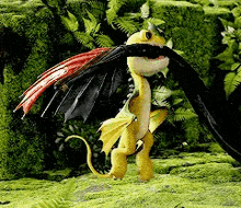 a yellow dragon with black wings is standing in a grassy field .