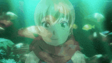 a girl in a scarf is swimming in the water with fish behind her