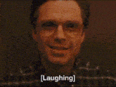 a man wearing glasses is smiling and laughing with the words laughing written below him .
