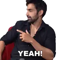 a man in a black shirt is pointing at something and the word yeah is above him