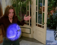 a woman is standing in front of a door with a blue light coming out of it and the website gickr.com is visible