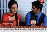 a man is holding a microphone and talking to a woman on a tv show