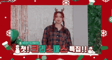 a girl wearing a plaid shirt and a reindeer headband is standing in front of a christmas background .