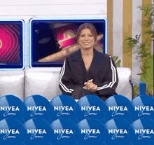 a woman is sitting on a couch in front of a wall of nivea creme advertisements