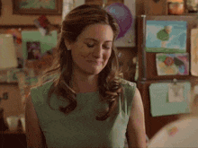 a woman in a green dress stands in front of a fridge
