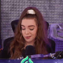 a woman is sitting in front of a microphone in a purple room .