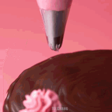 a chocolate cake is being decorated with pink frosting and the words mr. cakes are on the bottom