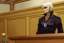 a man wearing sunglasses stands at a podium with a necklace that has the letter g on it