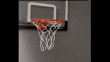 a basketball is going through a basketball hoop on a wall ..