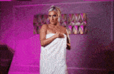 a woman wrapped in a white towel is standing in a room with purple lights .