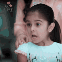 a little girl with a surprised look on her face is wearing a shirt that says " fairy "