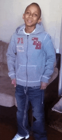 a young boy wearing a gray hoodie with the number 71 on it