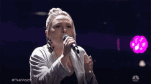 a woman singing into a microphone with #thevoice on the bottom