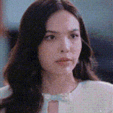 a close up of a woman 's face with a blurred background and a white shirt .