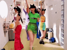 a group of girls are dancing in a hallway and one of them is wearing a green shirt that says com