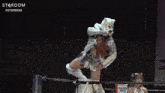 a woman in a mask is standing in front of a stardom sign