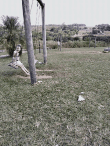 a little girl sits on a swing in a park