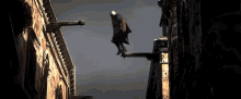a man is hanging from a building with a gray sky behind him