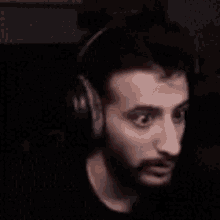 a man with a beard is wearing headphones and making a face .