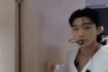 a man wearing a white robe and a microphone in his mouth is standing next to a door .