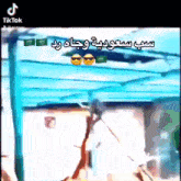 a man is standing under a blue canopy with arabic writing on it
