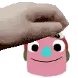 a hand is putting a pink cartoon character on top of a pink object .
