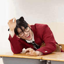 a young man wearing glasses and a cat ear headband is laying at a desk .