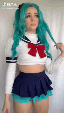 a girl with blue hair is wearing a sailor outfit with a red bow