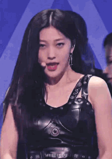a woman wearing a black leather top with the word guess on the front