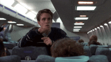 a man sitting on an airplane with a sign that says emergency exit on it
