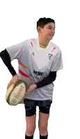 a boy in a mbc shirt holds a rugby ball in his hand