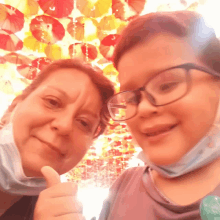 a woman and a boy are posing for a picture with umbrellas hanging from the ceiling behind them
