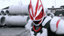 a red and white power ranger is standing in front of a stack of pipes .