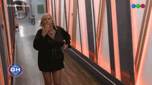 a woman in a black dress is walking down a hallway with the letters gh above her