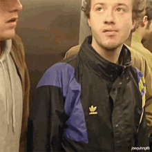 a man wearing an adidas jacket is standing in an elevator