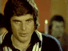a man with a striped shirt is looking at the camera