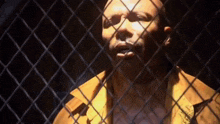 a man is behind a chain link fence with his eyes closed