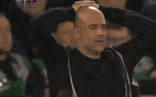 a bald man is standing in front of a crowd .