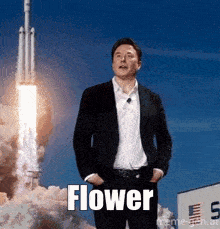 a man in a suit is standing in front of a rocket with the word flower written in front of him .