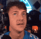 a man wearing headphones and a blue shirt is looking up at something